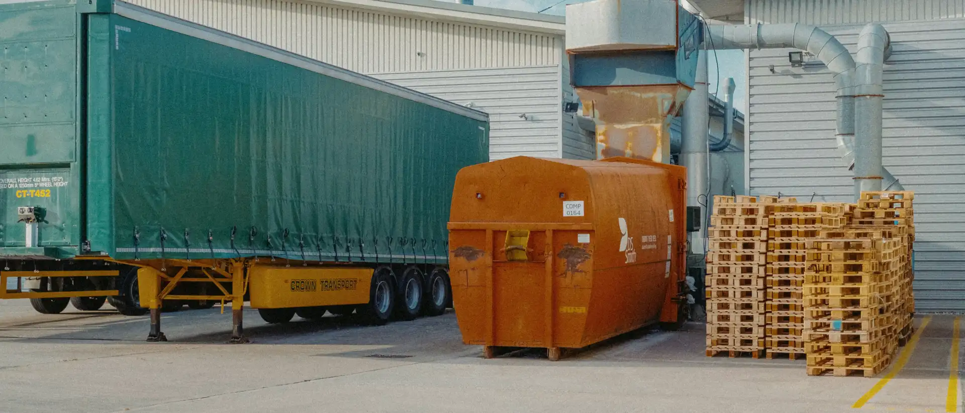 Curtain-side trailer and stacked pallets at a warehouse loading area